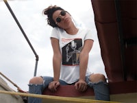 a woman wearing jeans and a t - shirt sitting on a ledge