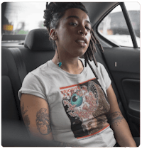 a woman sitting in the back seat of a car with tattoos