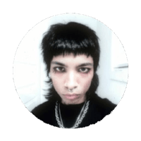 a man with black hair and a chain around his neck