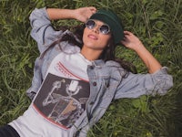 a woman laying in the grass wearing sunglasses and a t - shirt